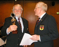 Den Pokal nimmt Hans-Jörg Karow vom Bezirksvorsitzenden Hans-Jürgen Müller entgegen